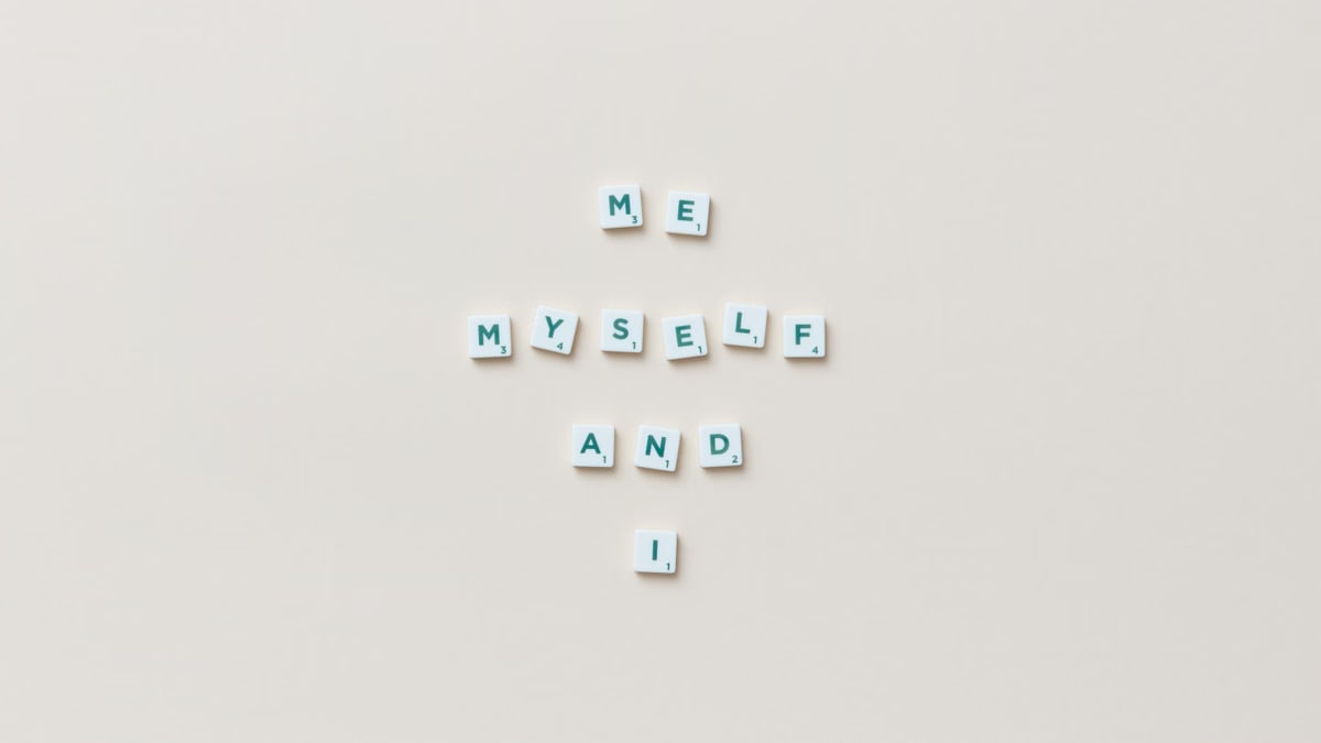 Minimalist composition of Scrabble tiles spelling 'Me, Myself, and I' on a white background.